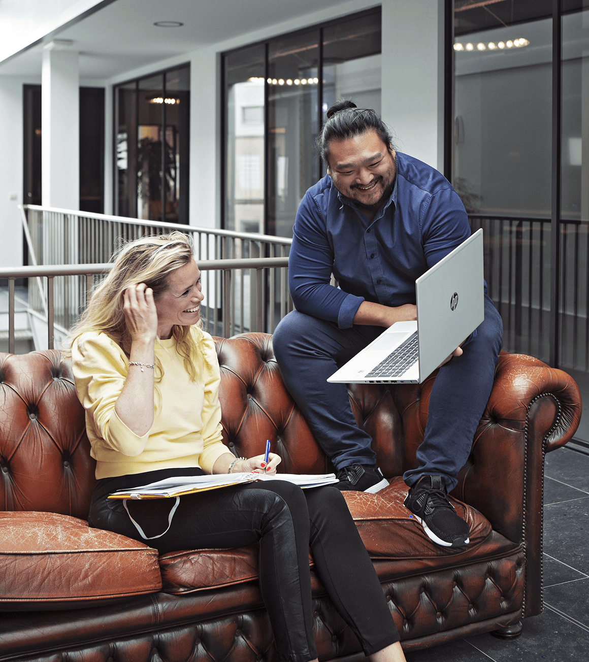 Twee collega's overleggen op de bank met een laptop
