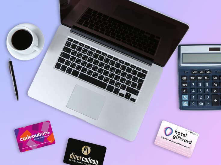 Laptop met rekenmachine, kop koffie en drie cadeaukaarten op een bureau