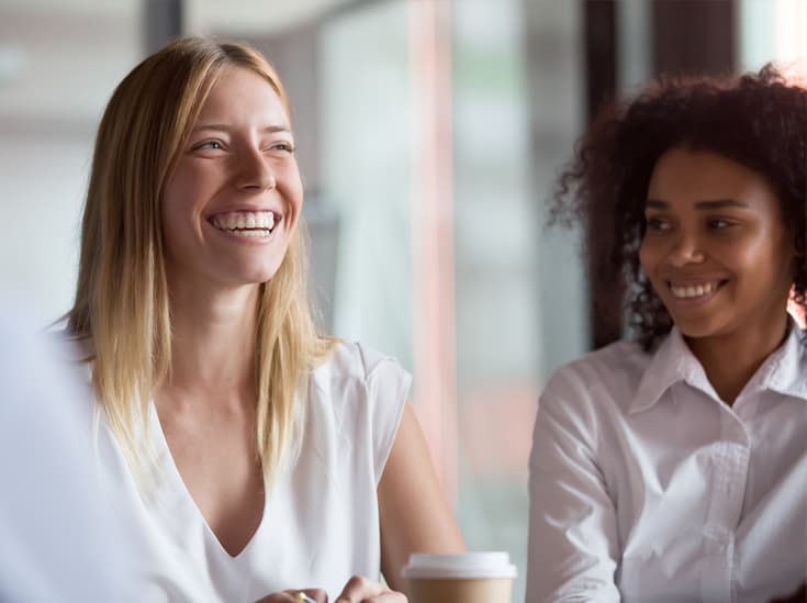 Twee lachende collega's in gesprek op kantoor